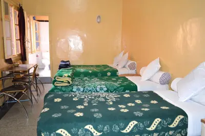 two beds in a hotel room with green sheets at Hotel Atlas Ouarzazate in Ouarzazate