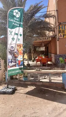 a sign in front of a building with a restaurant at Hôtel restaurant Palmiers in Alnif