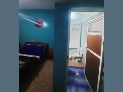 a bathroom with a toilet and a bedroom with blue walls at Hôtel restaurant Palmiers in Alnif