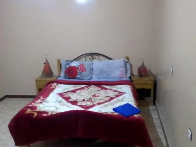 a bedroom with a bed with a red and white blanket at Hôtel restaurant Palmiers in Alnif