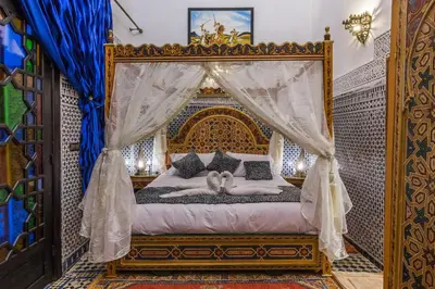 a bedroom with a canopy bed with two people laying on it at Riad Ghita Palace in Fès