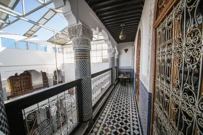an internal corridor of a building with columns and tile floors at Riad Ghita Palace in Fès