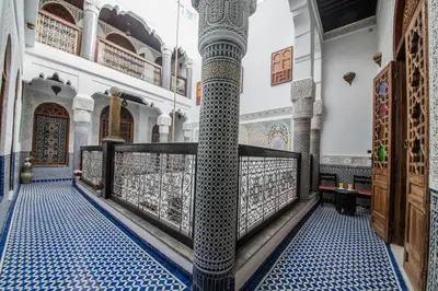 a room with a column in a mosque with blue and white tiles at Riad Ghita Palace in Fès