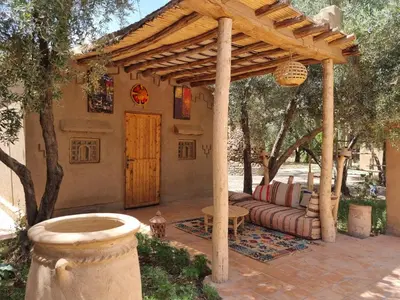 a patio with a wooden pergola and a couch at Eco-Ferme Tamalait Skoura in Skoura