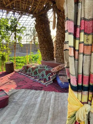 a person laying on a rug under a tent at Eco-Ferme Tamalait Skoura in Skoura