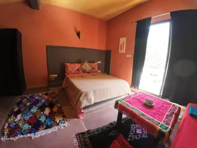a bedroom with a bed and a table and a window at Ourika Atlas Tigmi in Ourika