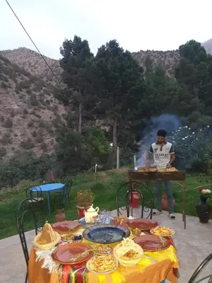 a man is cooking food at a table with a table at Ourika Atlas Tigmi in Ourika