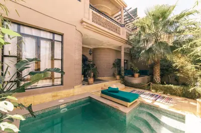 a house with a swimming pool and a palm tree at The Kozyhome in Ouarzazate