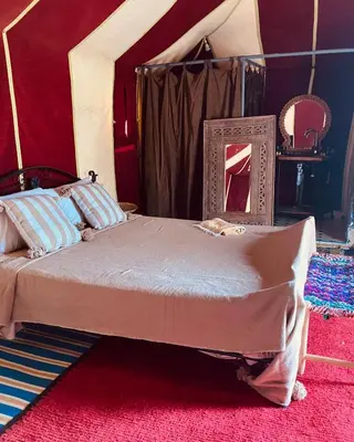 a bedroom with a large bed with a mirror at Majorelle Desert Camp in Zagora
