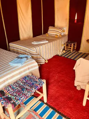 a room with two beds and a red rug at Majorelle Desert Camp in Zagora
