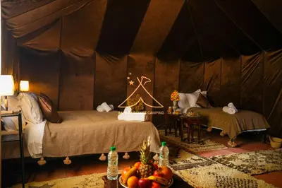 a bedroom with two beds and a table with fruit on it at Sahara Desert Camping - Merzouga Luxury Camp in Erfoud