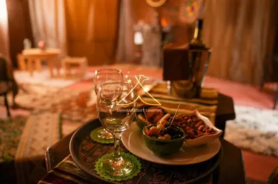 a table with a plate of food and wine glasses at Sahara Desert Camping - Merzouga Luxury Camp in Erfoud