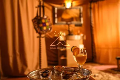 a table with a glass of wine and a plate of food at Sahara Desert Camping - Merzouga Luxury Camp in Erfoud