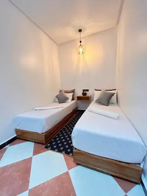 two beds in a room with a checkered floor at Salam appartement climatisé hiver et été in Azrou