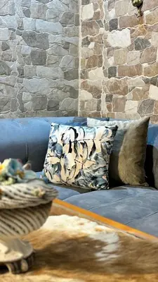 a blue couch with pillows and a stone wall at Salam appartement climatisé hiver et été in Azrou