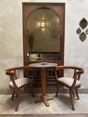 a wooden table with two chairs and a mirror at Riad Dar Rafti - Restaurant & Rooms with en-suite in Fès