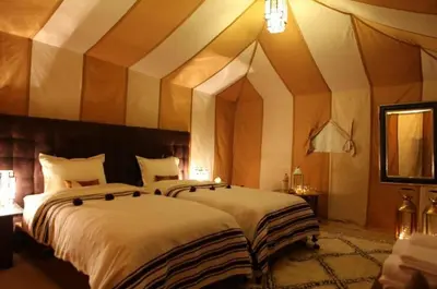 two beds in a large room with a ceiling at sand rose luxury camp in Merzouga