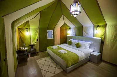 a bedroom with a large bed with a green roof at sand rose luxury camp in Merzouga