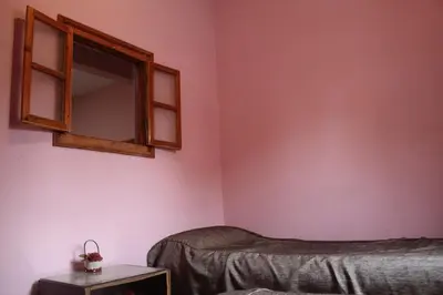 a bedroom with pink walls and a mirror at Chez l'habitant (Ba Omar) in Zagora