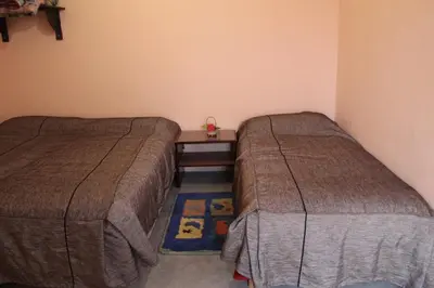 a bedroom with two beds and a small table between them at Chez l'habitant (Ba Omar) in Zagora