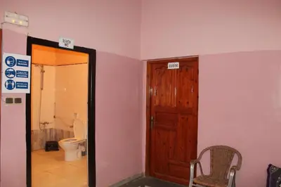 a bathroom with a toilet and a wooden door at Chez l'habitant (Ba Omar) in Zagora