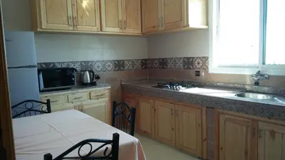 a kitchen with wooden cabinets and a table and a sink at LOGEMENT HOTEL et NAVETTE GRATUITE in Fès