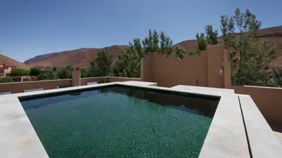 a swimming pool in a backyard with mountains in the background at Chez Ichou in Aït Idaïr
