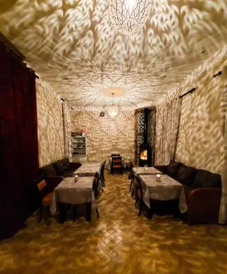 a dining room with tables and chairs and a chandelier at Chez Ichou in Aït Idaïr