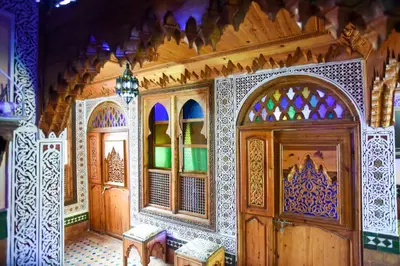 a room with wooden doors and stained glass windows at Riad Mehdi Meknès in Meknès