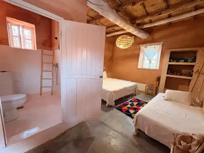 a bathroom with two beds and a toilet in a room at Tigmi Hamid Découverte des traditions et de la culture berbère in Aït Ben Haddou