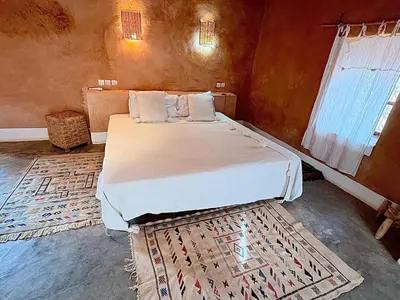 a bedroom with a bed in a room with a rug at Tigmi Hamid Découverte des traditions et de la culture berbère in Aït Ben Haddou