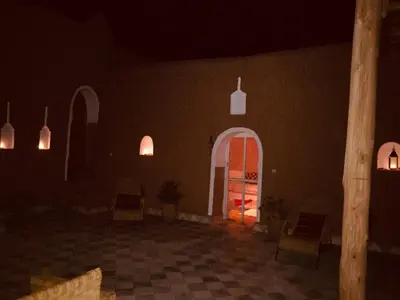 a room with a door and chairs at night at Tigmi Hamid Découverte des traditions et de la culture berbère in Aït Ben Haddou