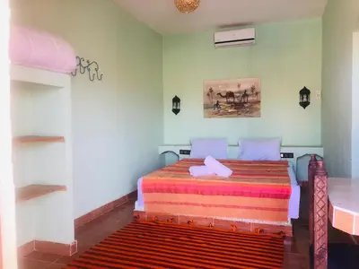 a bedroom with a bed with a colorful blanket at Riad Hotel Les Flamants in Merzouga