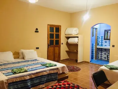 a hotel room with two beds and a door at Riad Hotel Les Flamants in Merzouga