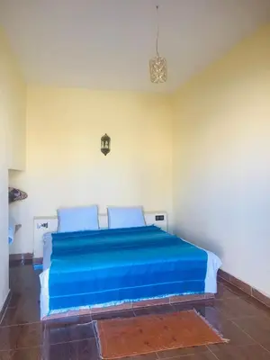 a bedroom with a bed with blue sheets at Riad Hotel Les Flamants in Merzouga