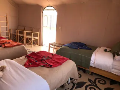 a room with three beds and a window at Mirage Luxury Camp in Merzouga