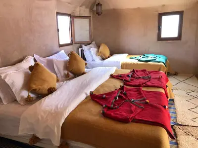a room with three beds with clothes on them at Mirage Luxury Camp in Merzouga
