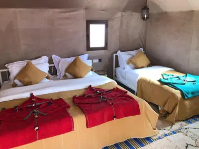 a room with two beds with red and blue sheets at Mirage Luxury Camp in Merzouga