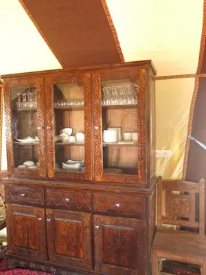 a wooden cabinet with dishes inside of it at Mirage Luxury Camp in Merzouga