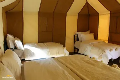 two beds in a room with white sheets and pillows at bassou luxury camp in Merzouga