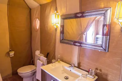 a bathroom with a sink and a toilet and a mirror at bassou luxury camp in Merzouga