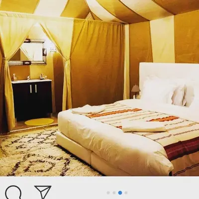 a bedroom with a large bed and a bathroom at bassou luxury camp in Merzouga