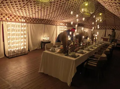 a man standing at a long table in a tent at bassou luxury camp in Merzouga