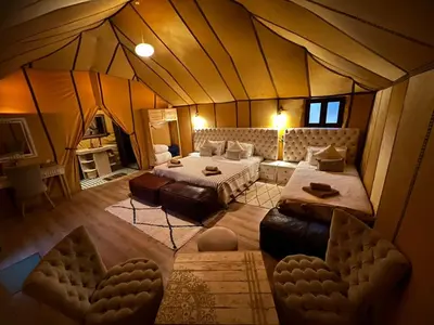 a large room with two beds in a tent at bassou luxury camp in Merzouga