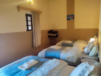 a room with three beds and a window at Sahara Sands Hotel in Merzouga