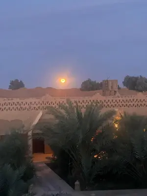 a view of a building in the desert with the sunset at Sahara Sands Hotel in Merzouga