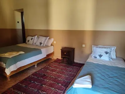 a room with two beds and a night stand and a bed sidx sidx at Sahara Sands Hotel in Merzouga