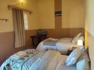 a bedroom with two beds and a window at Sahara Sands Hotel in Merzouga