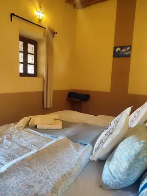 two beds in a room with yellow walls and a window at Sahara Sands Hotel in Merzouga