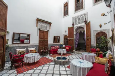 a living room with tables and chairs in a building at Riad Arabella in Fès